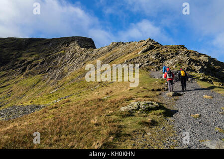 Tre gli escursionisti in avvicinamento alla codifica oltre il bordo affilato nel Parco nazionale del Lake District in Inghilterra. Foto Stock