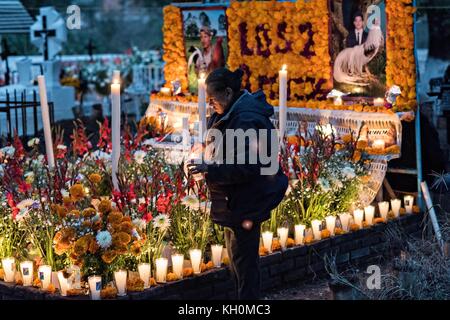 La madre di due fratelli uccisi lo stesso giorno accende candele sulla loro tomba decorata durante il giorno del festival dei morti 31 ottobre 2017 a Tzintzuntzan, Michoacan, Messico. Foto Stock