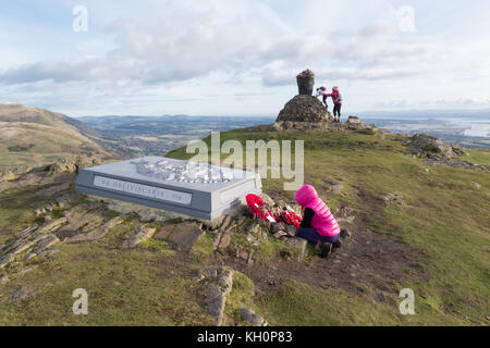 Dumyat Hill, Stirling, Scozia, Regno Unito. 11th Nov 2017. Tempo UK - in una bella giornata Armistizio luminoso in cima a Dumyat Hill, Stirling, una giovane ragazza legge memoriali e papaveri in un memoriale di Argyll e Sutherland Highlanders credito: Kay Roxby / Alamy Live News Foto Stock