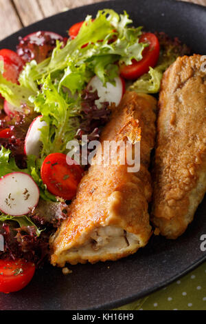 Fritti in un travagliato nasello e insalata fresca su una piastra di close-up verticale. Foto Stock