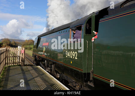 Locomotiva a vapore in attesa di discostarsi dalle bavature county park stazione ferroviaria con holcombe hill in background in bury LANCASHIRE REGNO UNITO Foto Stock