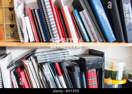 Un home office ripiani con impilati verticalmente libri, quaderni, cartelle, documenti e CD Foto Stock