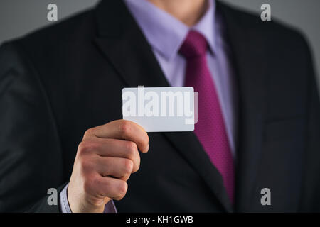 Imprenditore in abito elegante e con un tirante, mostra business card con copia spazio, studio shot Foto Stock