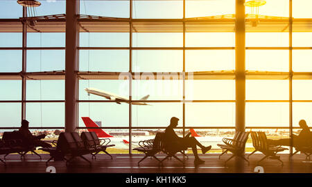Silhouette la gente in un aeroporto e aerei a sembrare dalla finestra. Foto Stock