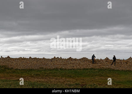 Un uomo constructes un cairn sulla spiaggia di Isola Santa Foto Stock