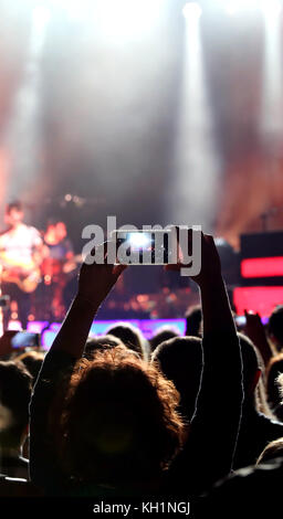 Ragazzina prende una foto durante un concerto dal vivo di una rock band Foto Stock