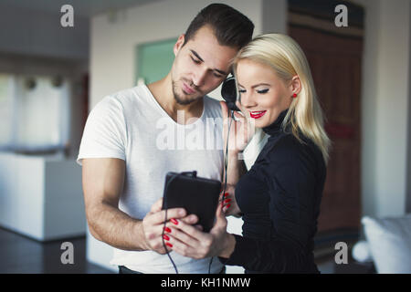 Giovane coppia caucasica ascoltando musica dal tablet a casa Foto Stock