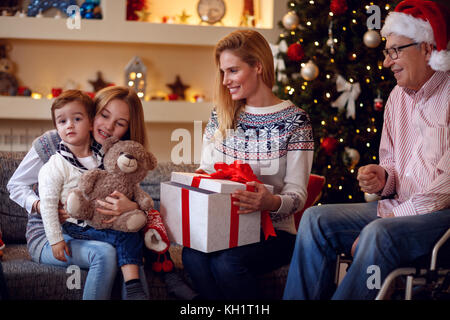 Lo scambio di regali di natale- famiglia felice a Natale regali di apertura insieme Foto Stock