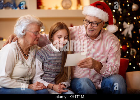 Sorridente nonni con il nipote guardare foto e condividere la memoria alla vigilia di Natale Foto Stock