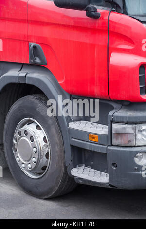 Close-up della parte anteriore cabina di un autocarro rosso, una scaletta mettalic su un camion, un paraurti e una ruota Foto Stock