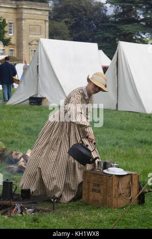 Versando acqua da un ferro battuto il bollitore in a coppe su un campo di battaglia encampment a Spetchley park Foto Stock