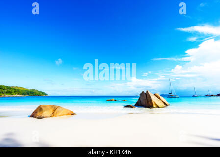 Pittoresca spiaggia da sogno con sabbia bianca e dorata di rocce di granito e catamarani in acqua turchese ed un cielo blu ad anse lazio a Praslin Island su Foto Stock