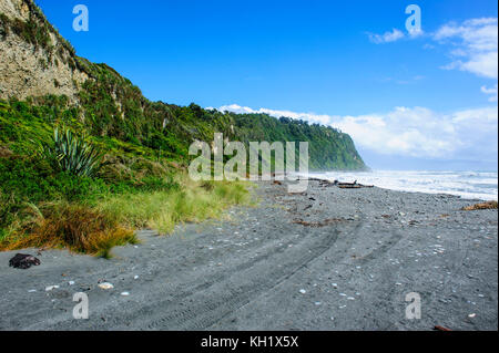 Grigio spiaggia rocciosa in okarito lungo la strada tra il ghiacciaio Fox e greymouth, Isola del Sud, Nuova Zelanda Foto Stock