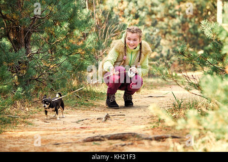 Ragazza all aperto con un piccolo cane.sorridente ragazza rilassante con il cane.bella ragazza sorridente in una camicia di protezione e il tappo con il piccolo cane un chihuahua cucciolo. ch Foto Stock