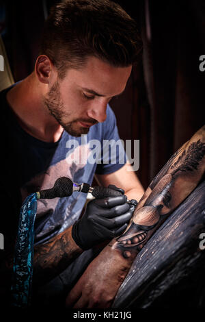 Professional tattoo artist fa un tatuaggio su una giovane mano d'uomo Foto Stock