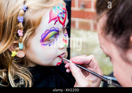 Ragazza giovane ottenendo faccia dipinta da un make up artist Foto Stock