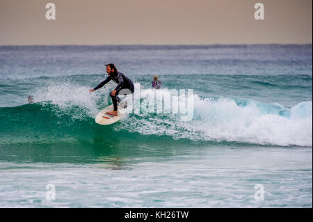 Un surfista cavalca un wave a Sydney iconici Bondi Beach, NSW, Australia Foto Stock