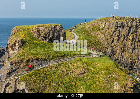 Migliaia di turisti visitano carrick-a-Rede ponte di corde nella contea di Antrim in Irlanda del nord, appeso 30m al di sopra di rocce e spanning 20m, principale di collegamento Foto Stock