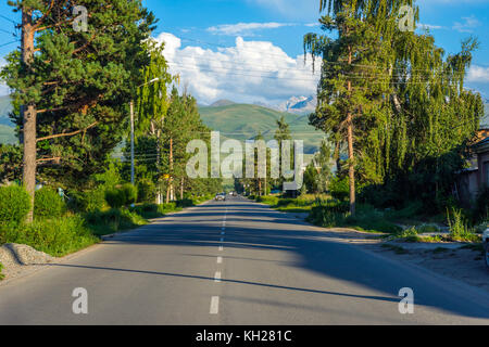 La strada verso le montagne verdi nella periferia di Karakol, Kirghizistan Foto Stock