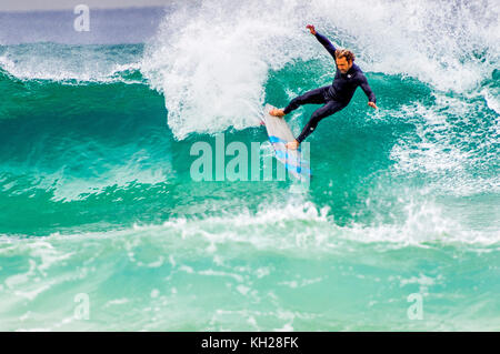 Un surfista cavalcare un onda a Sydney iconici Bondi Beach, NSW, Australia Foto Stock