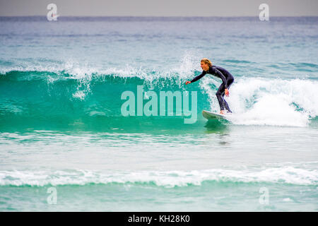 Un surfista cavalcare un onda a Sydney iconici Bondi Beach, NSW, Australia Foto Stock