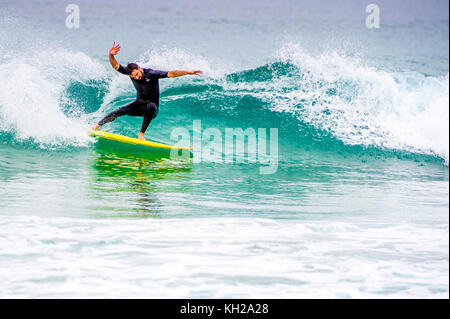 Un surfista cavalcare un onda a Sydney iconici Bondi Beach, NSW, Australia Foto Stock