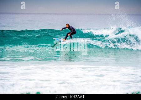 Un surfista cavalcare un onda a Sydney iconici Bondi Beach, NSW, Australia Foto Stock