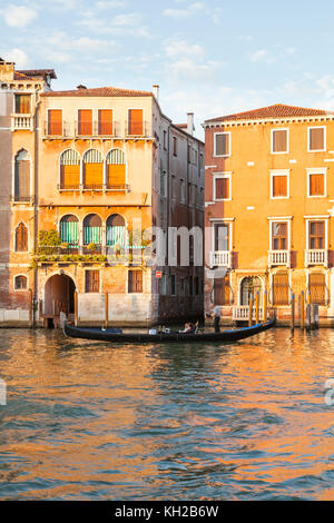 Gondola sul Canal Grande al tramonto, Cannaregio, Venezia, Italia canottaggio turisti passato Palazzo Bollani Erizzo nella luce dorata Foto Stock