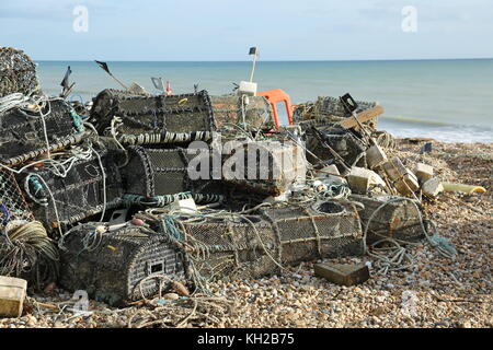 I vasi di aragosta dei pescatori si sono accumulati sulla spiaggia di ghiaia a Bognor Regis, West Sussex, Regno Unito. Soleggiato, giorno d'inverno. Mare calmo, bassa marea. Foto Stock