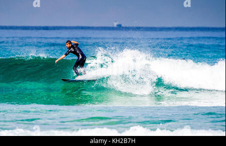 Un surfista cavalcare un onda a Sydney iconici Bondi Beach, NSW, Australia Foto Stock