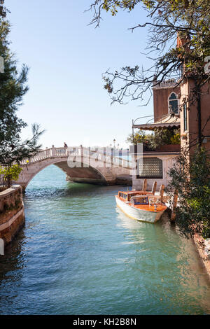 Vista del Ponte dei setti Martiri, Castello, Venezia, Italia lungo un tranquillo canale nei Giardini guardando verso la laguna con un taxi acqueo ormeggiato sotto Foto Stock