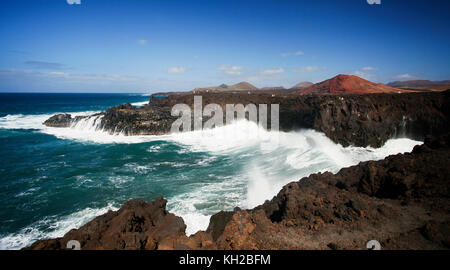 I turisti in una visualizzazione di balcone a Los Hervideros con grandi onde che si schiantano contro le rocce, scogliere e grotte, Lanzarote, Isole Canarie, Spagna Foto Stock