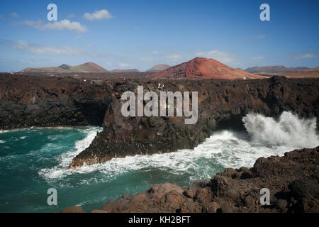 I turisti in una visualizzazione di balcone a Los Hervideros con grandi onde che si schiantano contro le rocce, scogliere e grotte, Lanzarote, Isole Canarie, Spagna Foto Stock