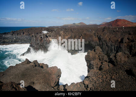 I turisti in una visualizzazione di balcone a Los Hervideros con grandi onde che si schiantano contro le rocce, scogliere e grotte, Lanzarote, Isole Canarie, Spagna Foto Stock