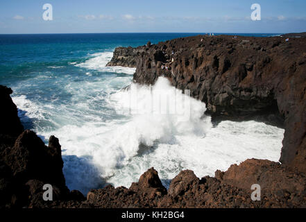 I turisti in una visualizzazione di balcone a Los Hervideros con grandi onde che si schiantano contro le rocce, scogliere e grotte, Lanzarote, Isole Canarie, Spagna Foto Stock