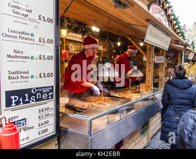 Stallo di alimentare con il personale di preparare il cibo per i clienti a Manchester Mercatino di Natale in piazza Albert, UK presa il 11 Nov 2017 Foto Stock