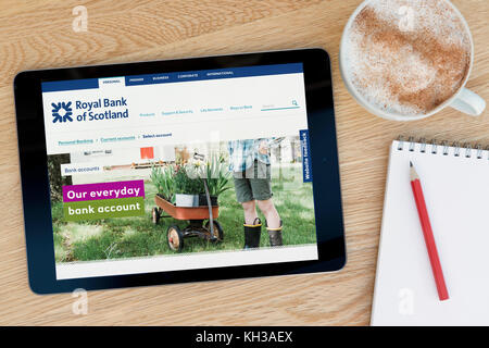 La banca RBS funzionalità del sito su un iPad dispositivo tablet pc che si appoggia su una tavola di legno accanto a un blocco note e matita e una tazza di caffè (editoriale solo) Foto Stock