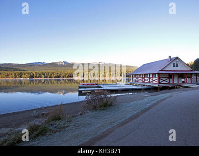Un tranquillo lago con red canoe pronto per essere immesso nel lago ancora, a fianco di una montagna Foto Stock