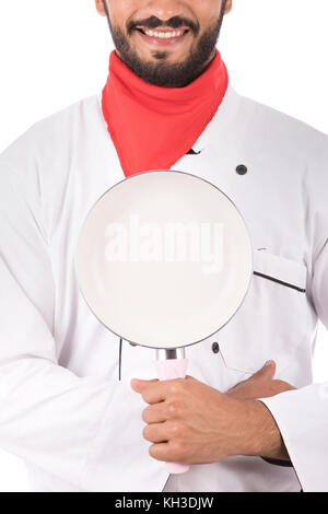 Tagliate il colpo di un felice barba giovane chef sorridente e tenendo un pan, ragazzo indossa bianco uniforme dello Chef e chef di Bianca Cappello, isolati su sfondo bianco Foto Stock