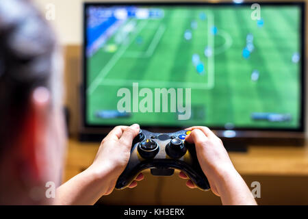 Close up di mani femminili in possesso di una centralina del joystick durante la riproduzione di un video giochi a casa, la profondità di campo ridotta sulle mani Foto Stock