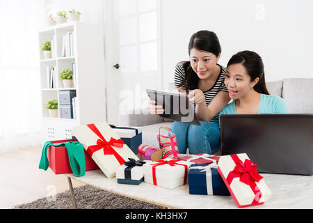 Sorridenti ragazze attraenti utilizzando tampone mobile computer online shopping insieme e schermo di puntamento a scelta di estate vendita merci a casa. Foto Stock