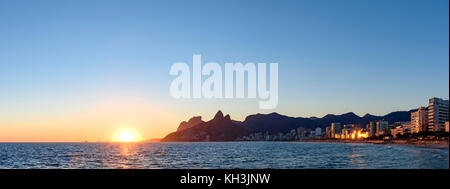 Tramonto panoramico in pietra Arpoador, spiaggia di Ipanema con edifici e colline a Rio de Janeiro Foto Stock