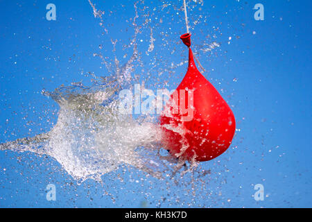 Esplosione di palloncino pieno di acqua su sfondo cielo Foto Stock