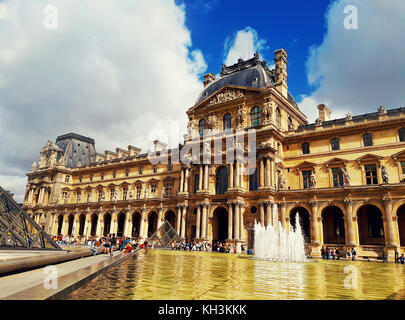 Ala Richelieu del Louvre con fontana, turisti e la Piramide di vetro a Parigi, Francia. Foto Stock