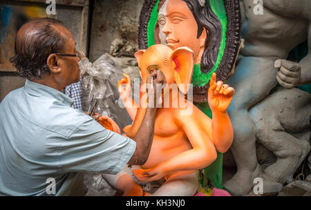 Un artigiano che applica i tocchi finali all'idolo di Lord Ganesha prima del festival Ganesh Chaturthi nella zona di Kumartuli di Kolkata, in India. Foto Stock