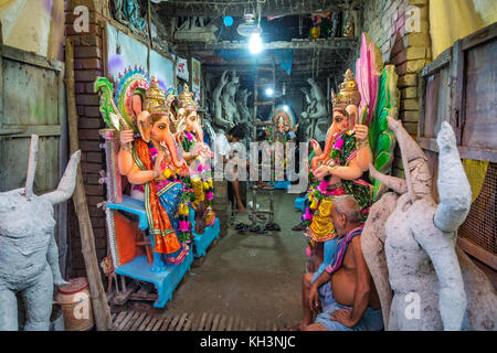 Piccoli artigiani locali studio a Kolkata, kumartuli area con molteplici divinità indiana di divinità Indù del display per la stagione festiva. Foto Stock