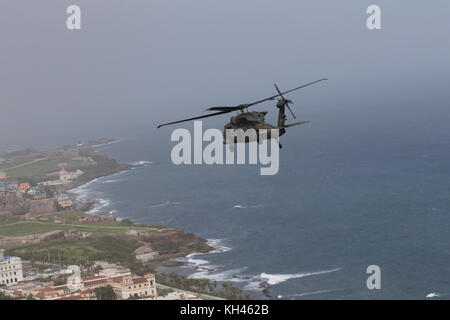 Un UH-60M Blackhawk elicottero dal 3° Battaglione, 501 Reggimento di aviazione, combattere la Brigata Aerea, 1° Divisione Corazzate vola su San Juan, Puerto Rico, 18 ottobre 2017, mentre la voce di Utuado per la fornitura di cibo e di acqua da FEMA ai suoi residenti a seguito della devastazione causata dall'uragano Maria. Foto Stock