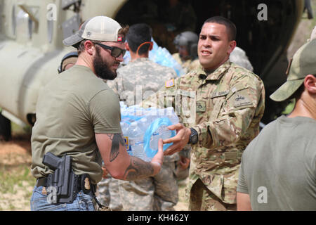 I soldati della Prima Divisione Corazzate contro la Brigata Aerea e gli agenti con il San Juan Investigation scaricare la CH-47 elicottero Chinook per la fornitura di cibo e di acqua da FEMA per i residenti di Utuado, Puerto Rico, 18 ottobre 2017, a seguito della devastazione causata dall'uragano Maria. Foto Stock