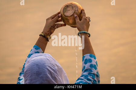 Donna indù che offre acqua al fiume Gange come parte di un rituale a varanasi ghat, India. Foto Stock