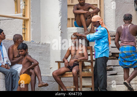 L'uomo con la sua testa rasata come parte di un rituale Indù presso il fiume Gange ghat a varanasi india. Foto Stock